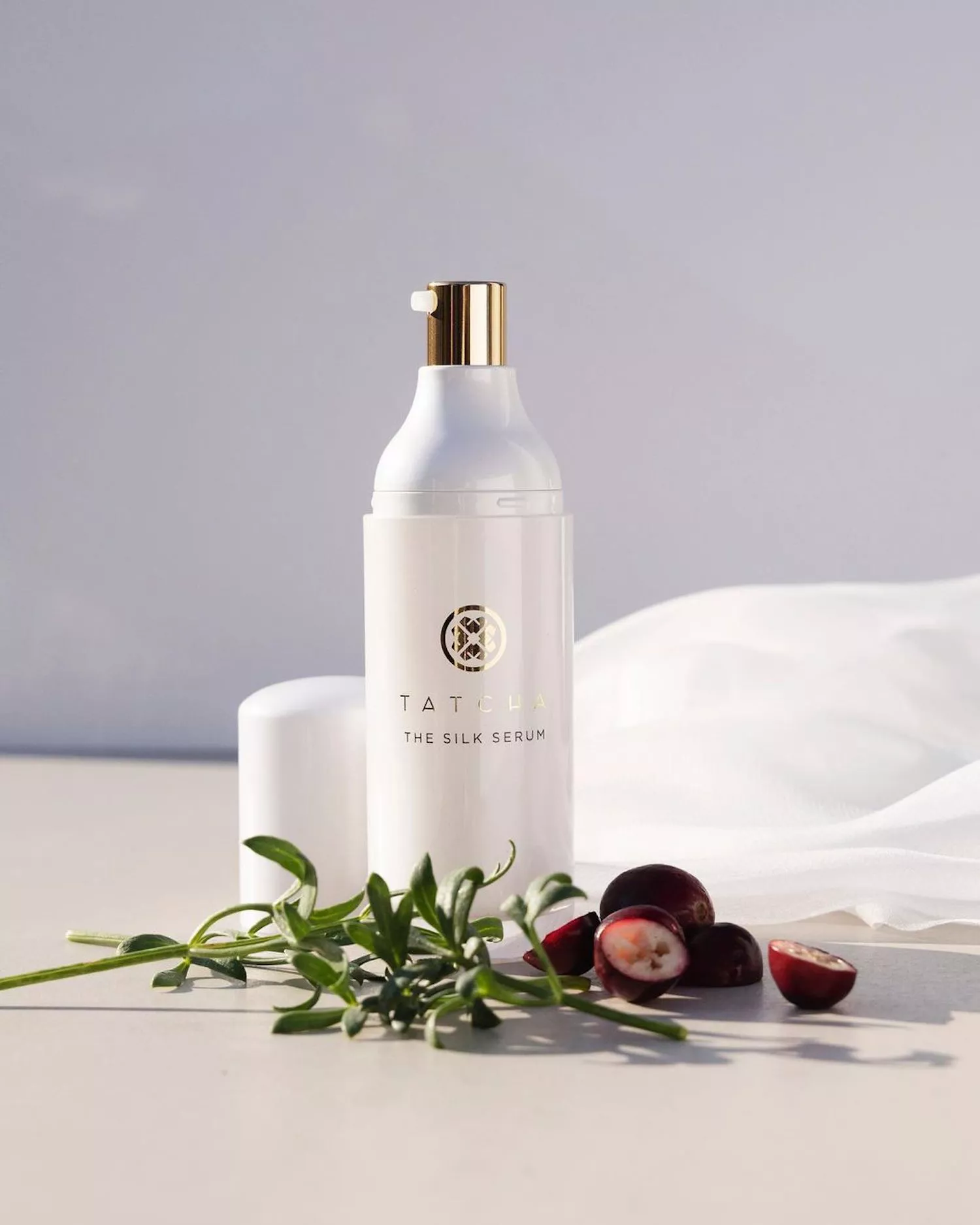 A bottle of Tatcha the Silk Serum, surrounded by cranberries