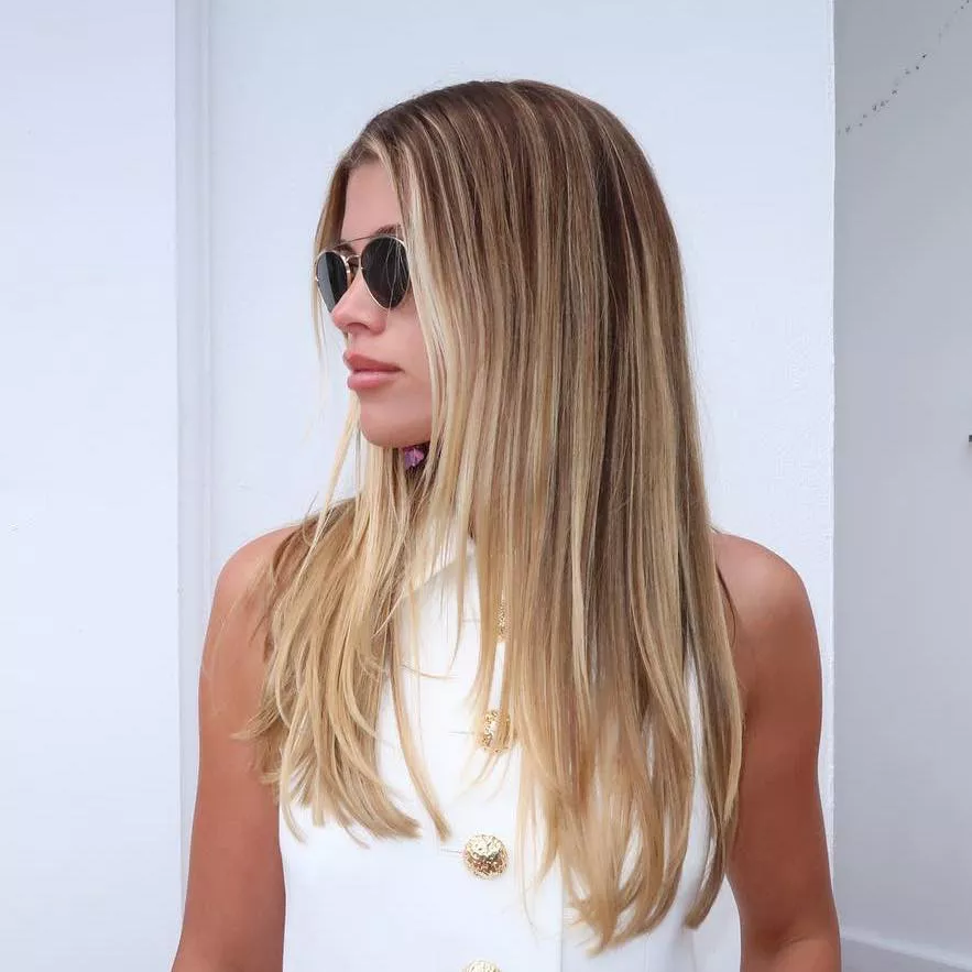 Sofia Richie wears a gradient balayage blowout, aviator sunglasses, and a white button-down top