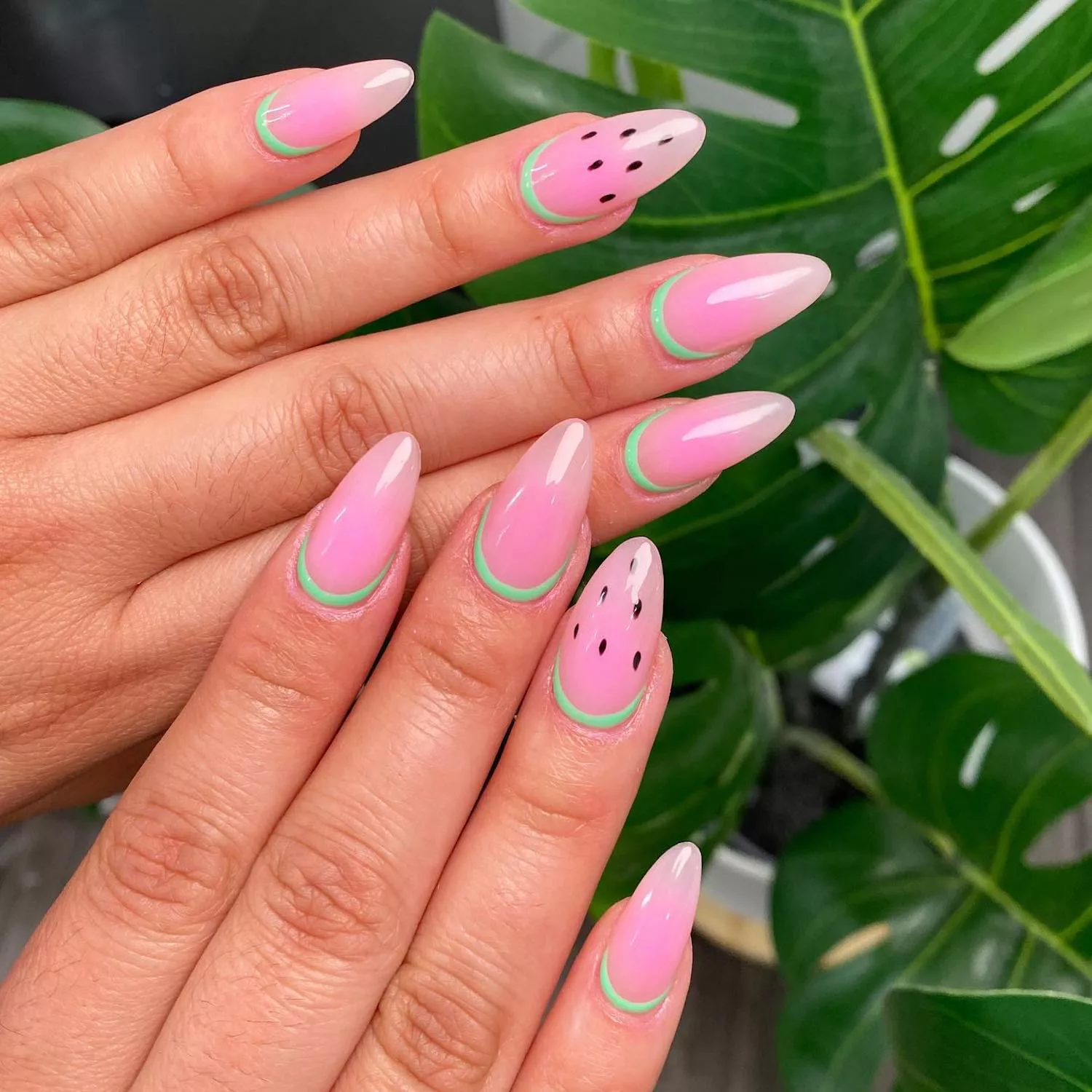 Translucent pink ombre watermelon nails with black dotted seed design and green cuticle rinds