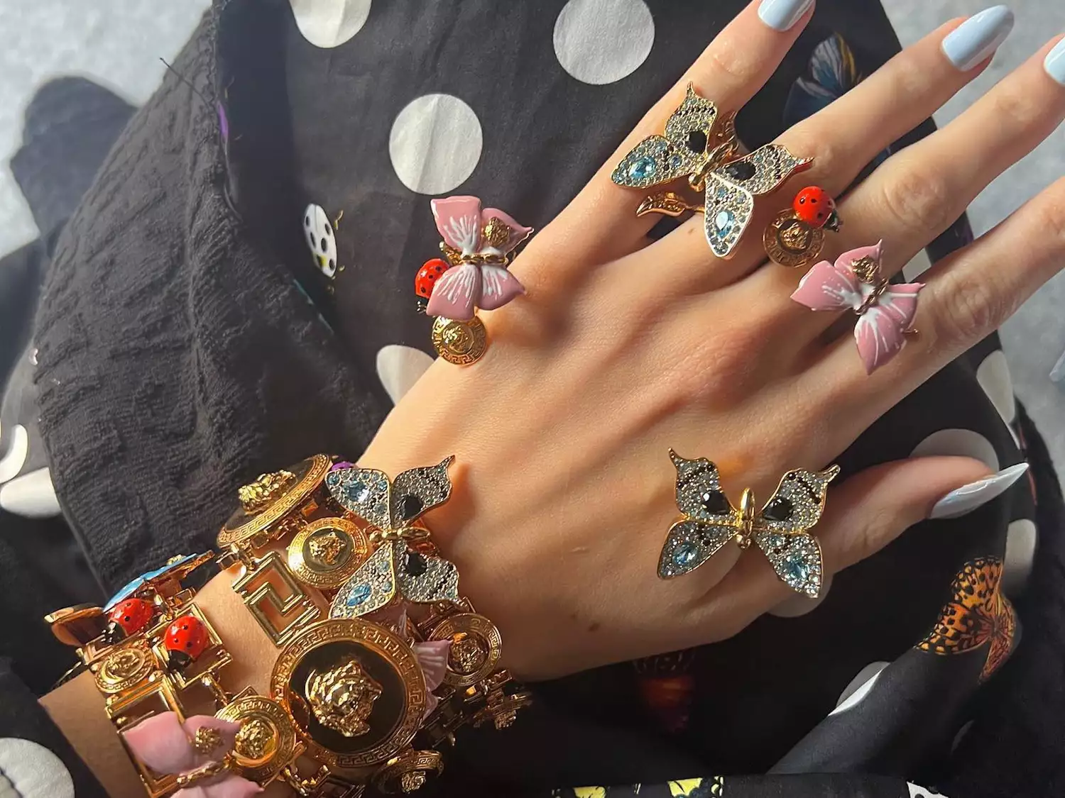 Hand with butterfly and ladybug Versace rings and bracelets