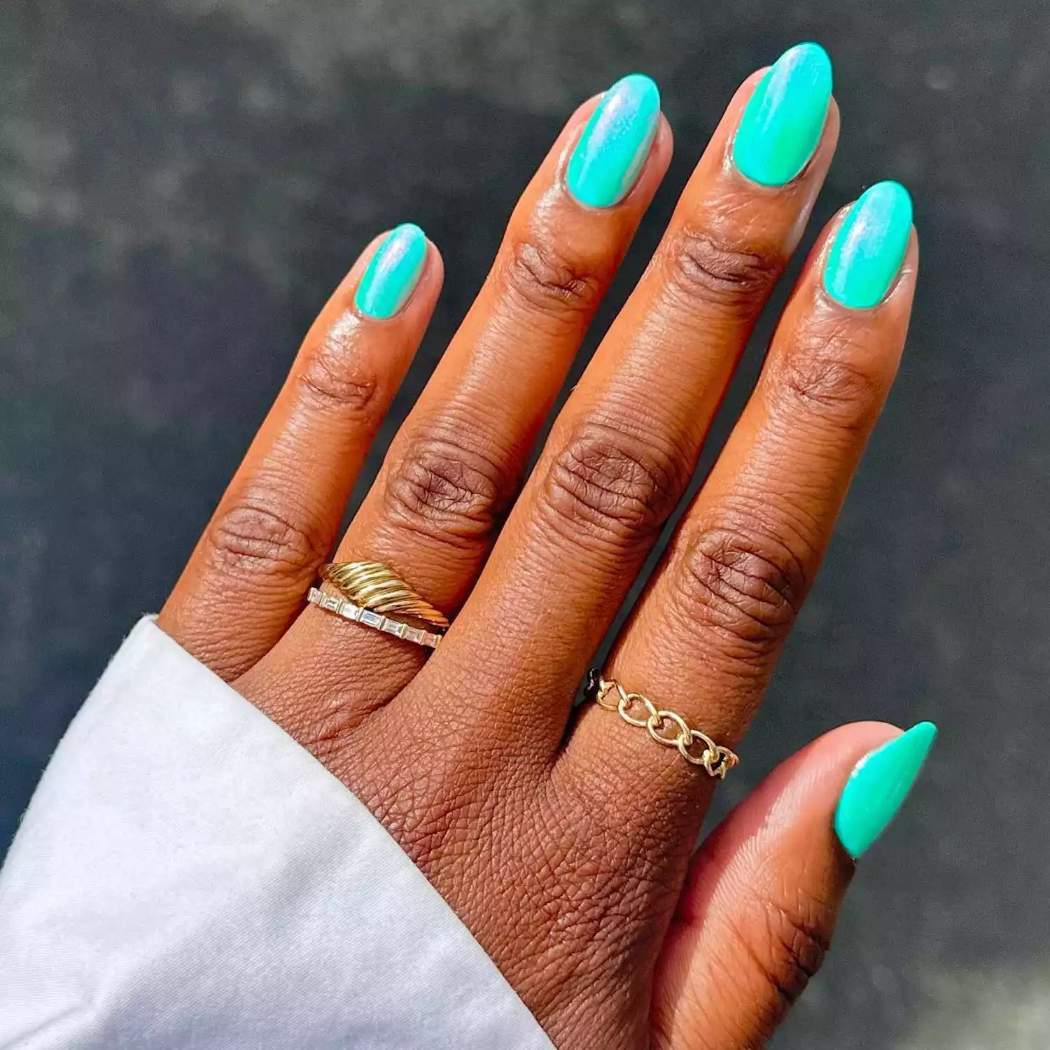 Turquoise teal manicure with iridescent chrome finish and gold rings