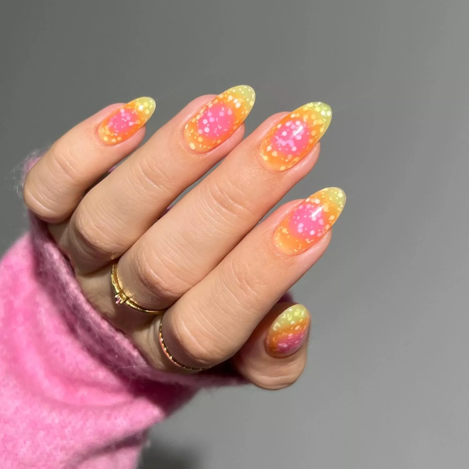 Manicure with pink and yellow aura design and confetti texture