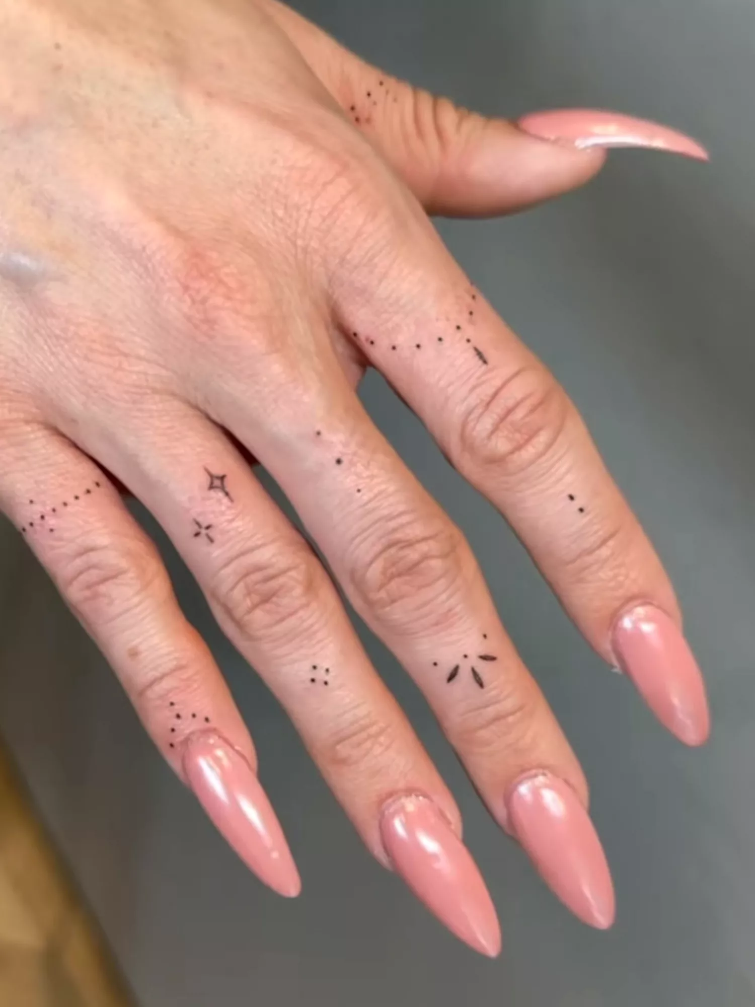 Delicate Finger Tattoos on Hand with Long Nails