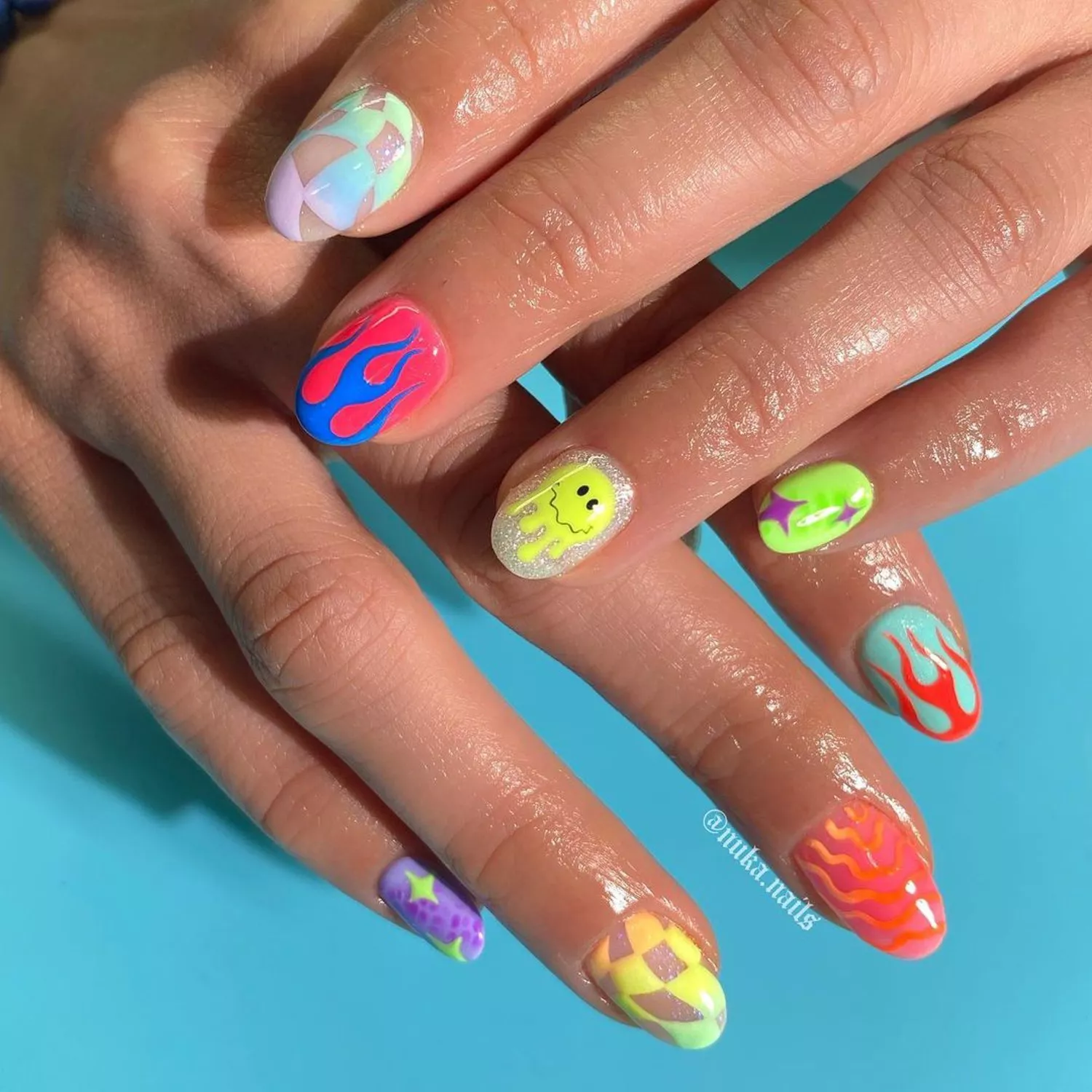 Manicure with abstract checkerboard, multicolored flame, melting smiley, and sparkle designs