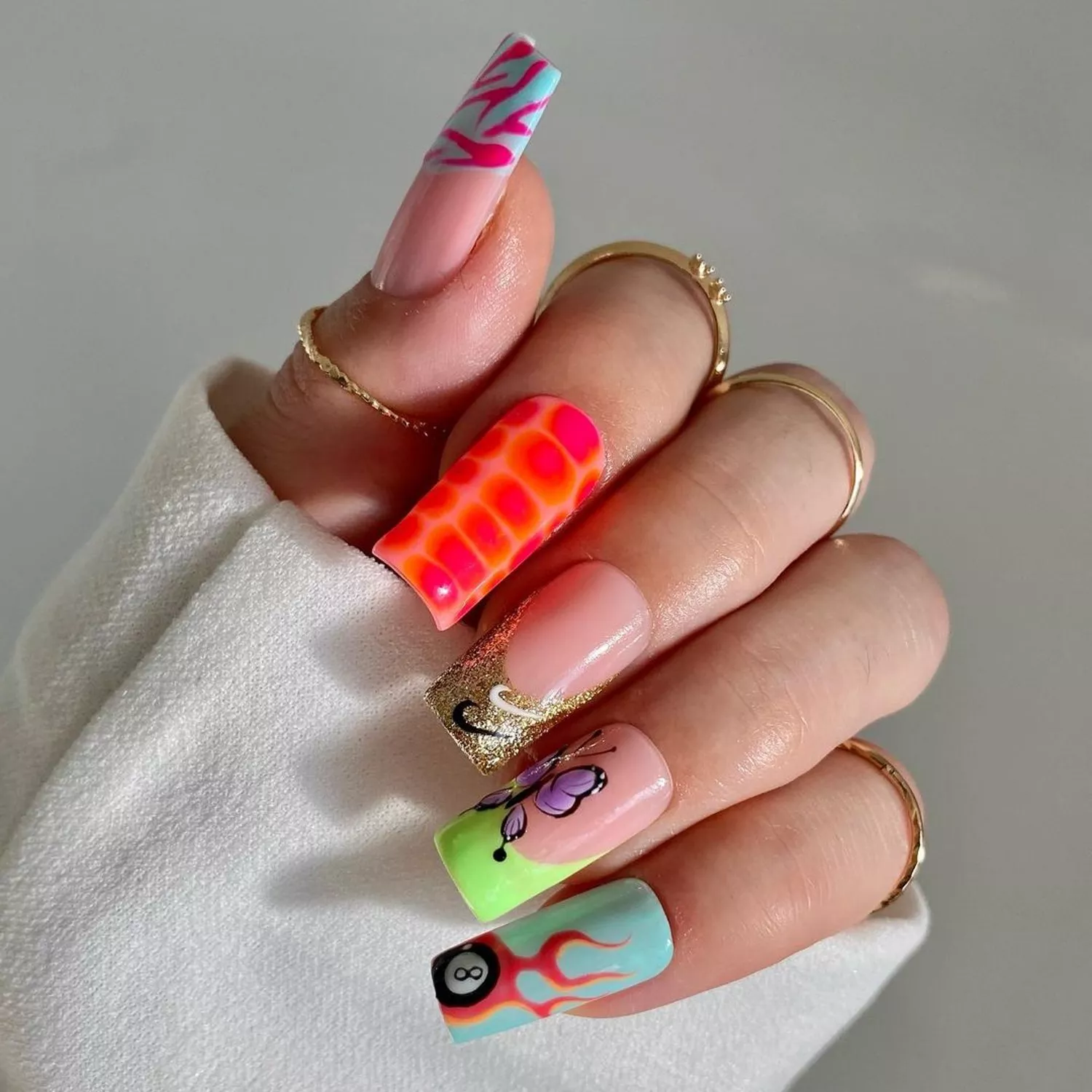 Mismatched manicure with flaming 8-ball, butterfly, glitter Nike, coral giraffe, and vivid zebra nails