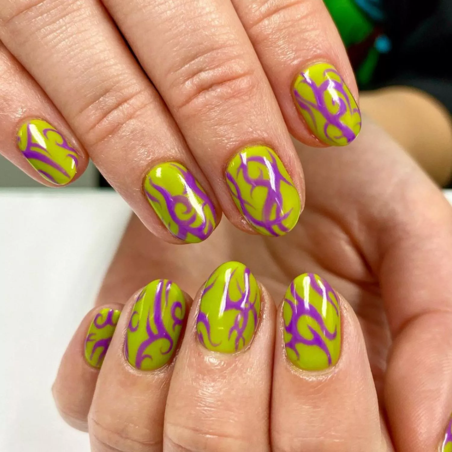 Lime green nails with neon purple swirling flame design