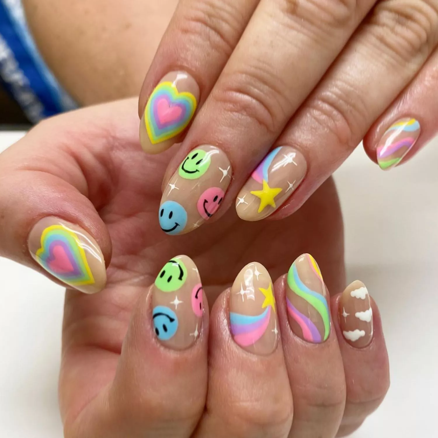 Y2K manicure with neutral base and colorful star, heart, wave, and smiley face designs