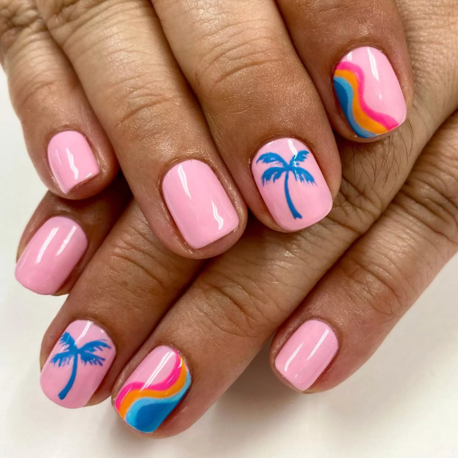 Candy pink manicure with rainbow wave and blue palm tree accent designs