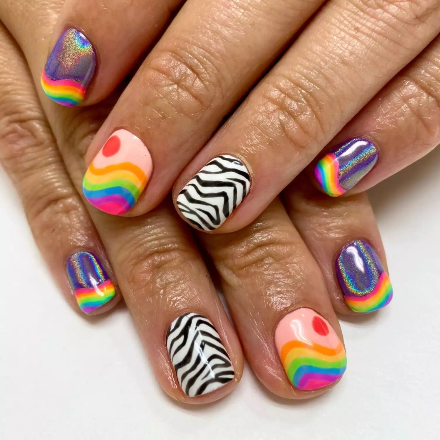 Manicure with rainbow wave designs, neutral and chrome bases, and zebra print accent nails