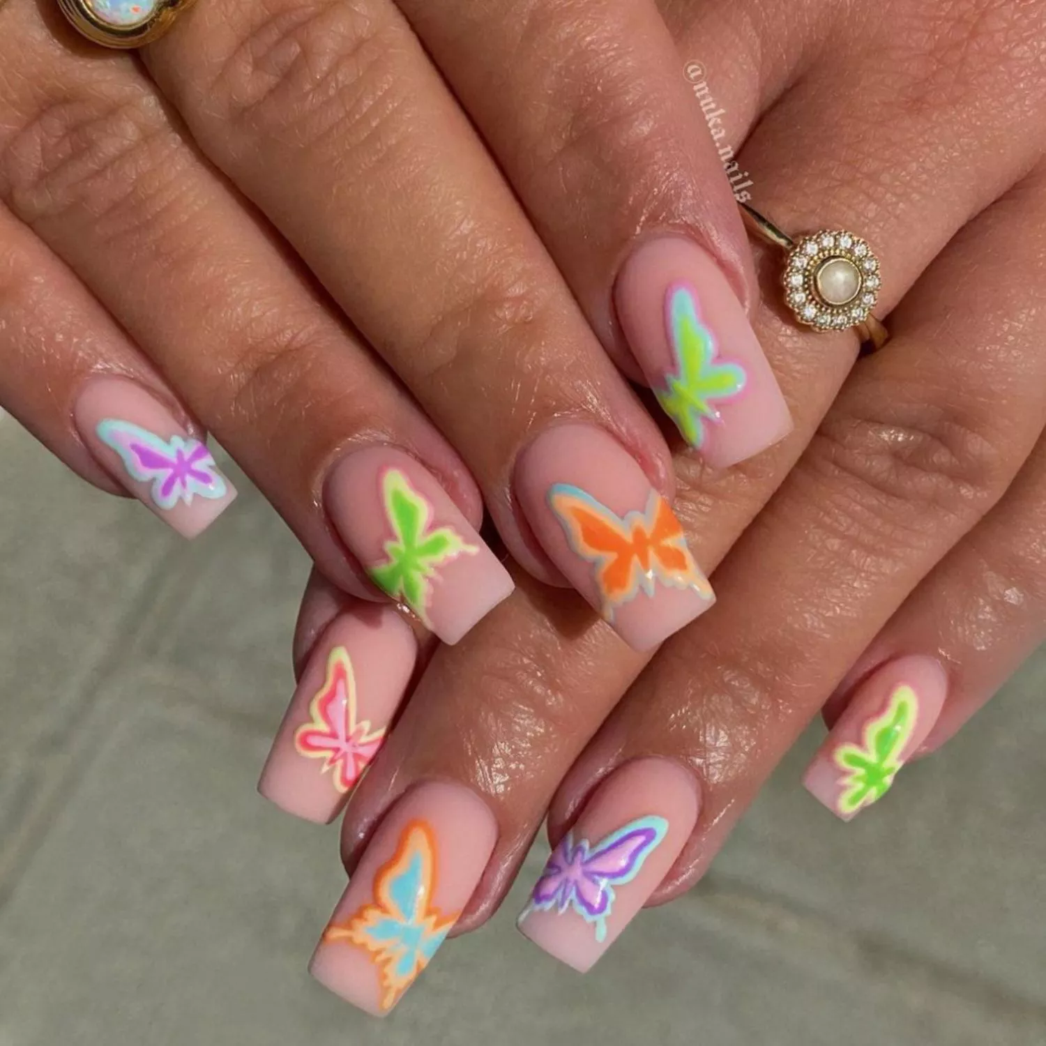 Neutral elongated manicure with neon butterfly designs