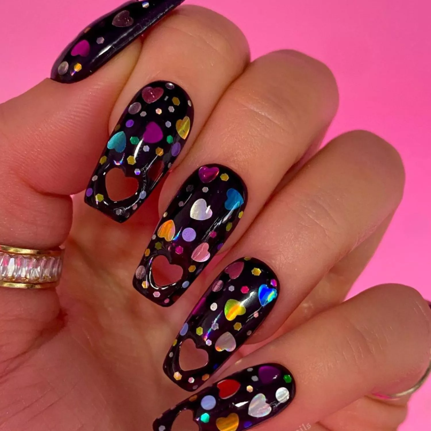 Long black manicure with colorful sparkles and hearts plus heart-shaped cutouts