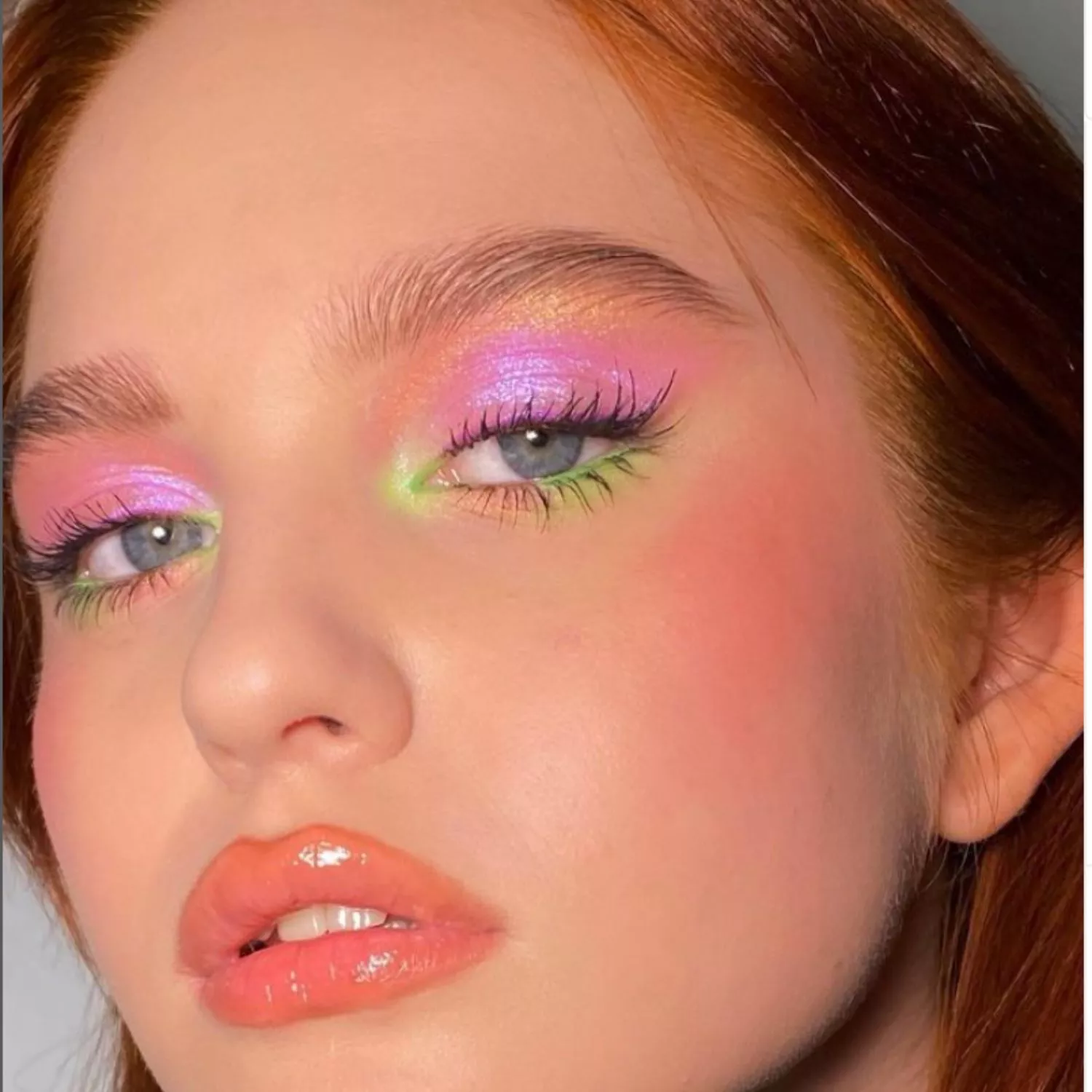Model with pink and gold eyeshadow with neon green watercolor tear duct and lower eyelid accents
